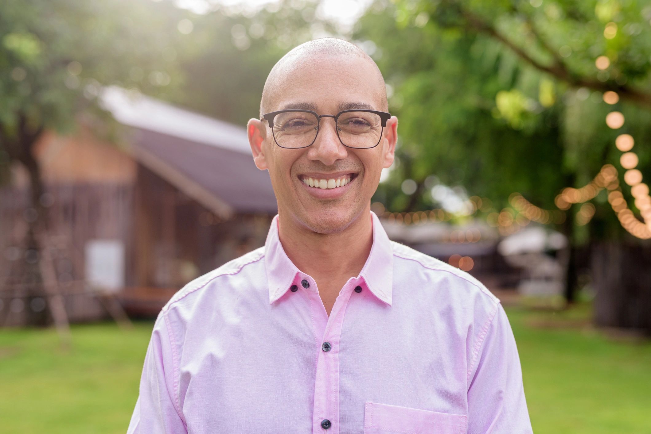 Bald man smiling outdoors in glasses